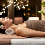 Frau entspannt sich im Spa, liegend auf einem Handtuch mit einer Blume im Haar.